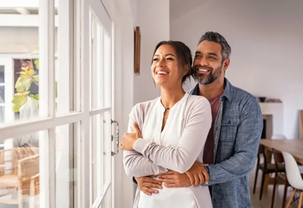 happy-couple-looking-outside-through-window